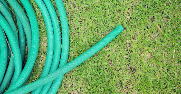 Stočená zavlažovací hadice na trávníku