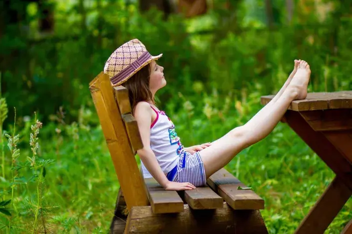 Holčička v klobouku na zahradní lavici Holčička v klobouku na zahradní lavici