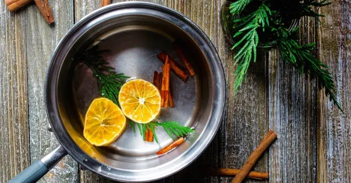 Plátky pomeranče a svitky skořice v hrnci s vodou Plátky pomeranče a svitky skořice v hrnci s vodou