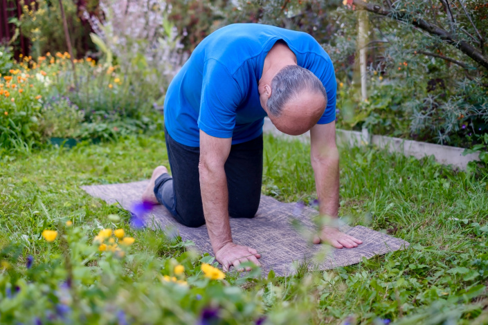 Muž cvičí na zahradě jógu