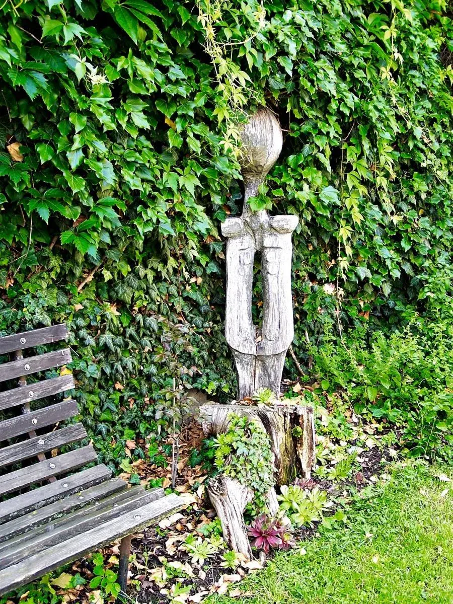 Socha vedle zahradní lavičky