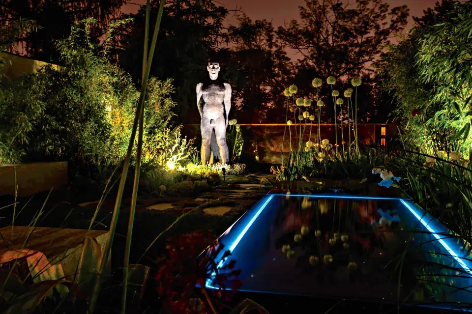 Osvětlený okraj bazénu a socha muže