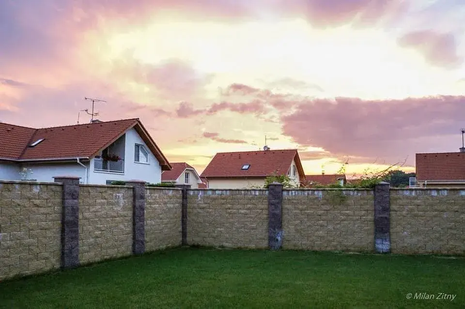 Pozemek s trávníkem a betonovým plotem