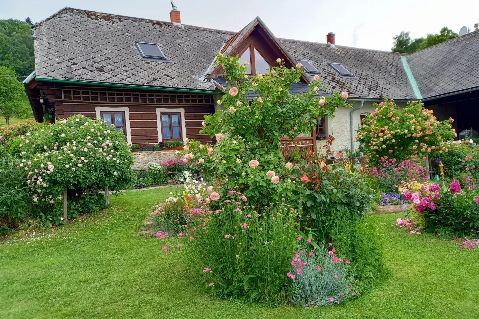 Zpola roubený dům a rozkvetlá zahrada