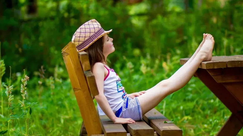 Holčička v klobouku na zahradní lavici