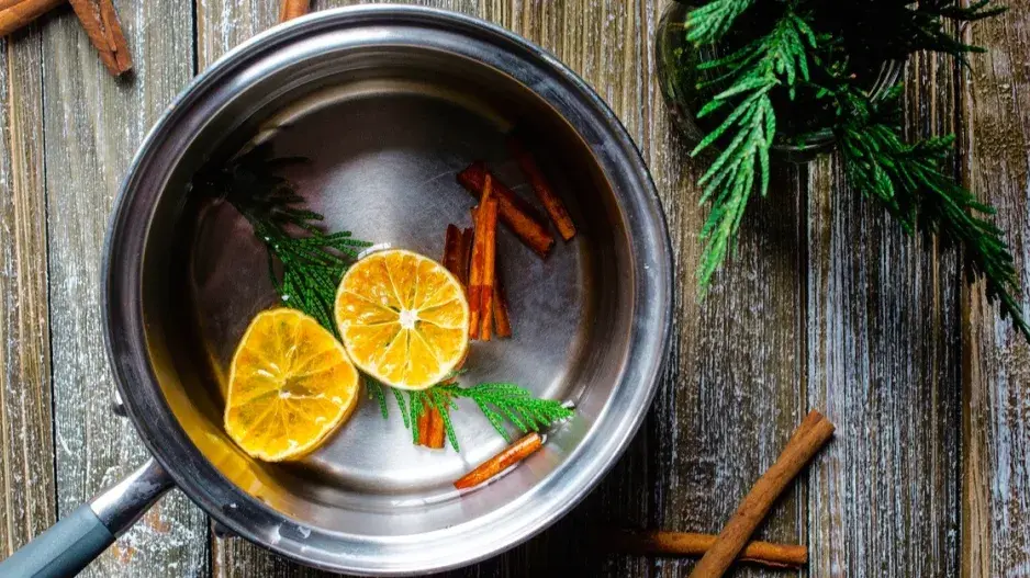 Plátky pomeranče a svitky skořice v hrnci s vodou