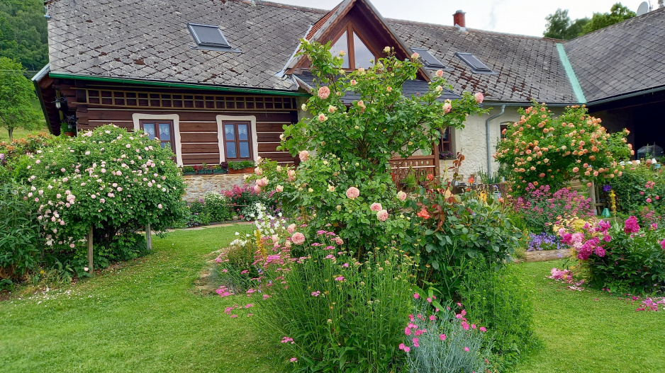 Zpola roubený dům a rozkvetlá zahrada